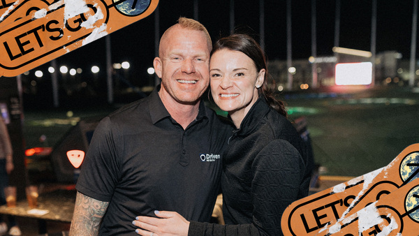 Scott and Tabitha Graham smile in front of the Top Golf playing field