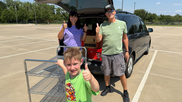 A retired couple and a young boy volunteer in a parking lot on a hot day in Texas.