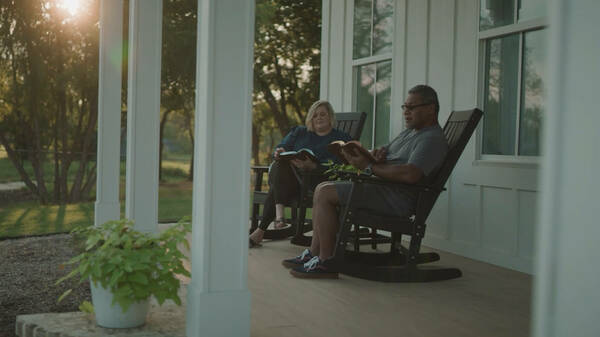Tagi and Kirsten Takape sit on a porch together reading their Bibles.